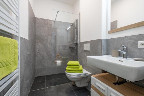 een badkamer met een wastafel en een toilet met groene handdoeken bij My Dahoam in Eben im Pongau