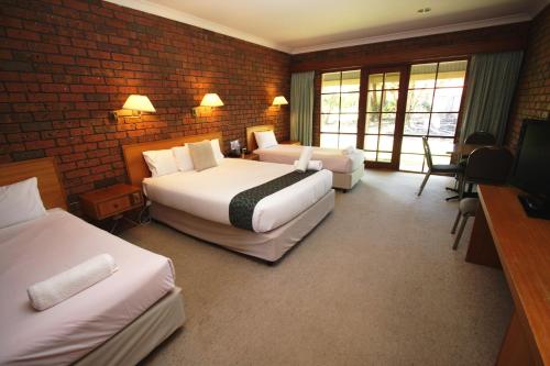 a hotel room with two beds and a brick wall at Grange Burn Motel in Hamilton