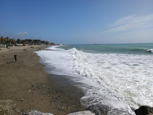a beach with people walking on the sand and water at savonaamare 2.0 in Savona