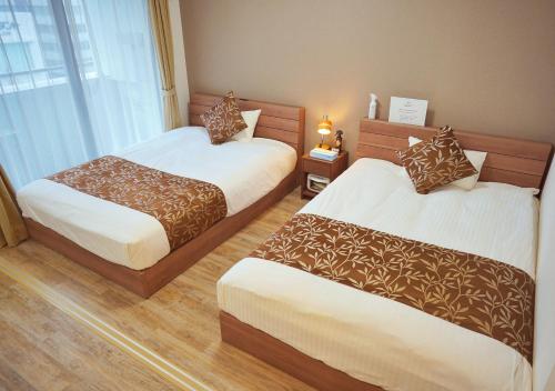 a hotel room with two beds and a window at Dream Inn Hakata in Fukuoka