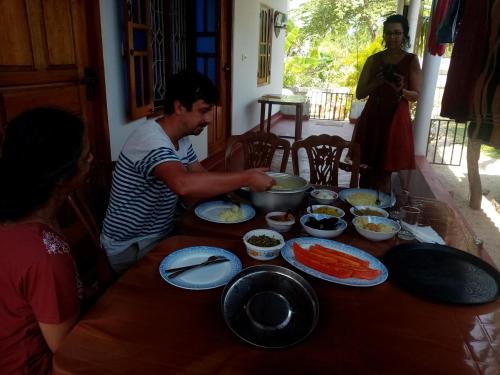 un grupo de personas sentadas alrededor de una mesa con comida en U new guest house, en Nilaveli