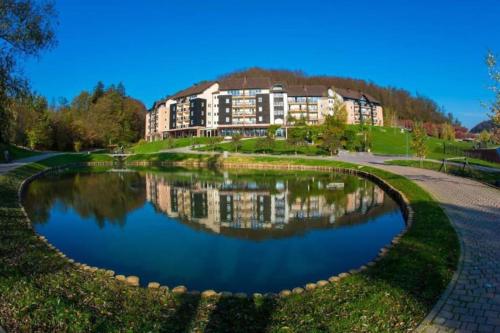 a hotel with a reflection in a pond at Aparthotel Rosa - apartma 204 in Podčetrtek