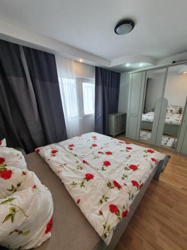 a bedroom with a bed with red flowers on it at Mândra Apartaments in Curtea de Argeş