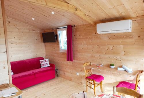 una camera con un divano rosso in una cabina di legno di Yourte A bourlon a Bourlon