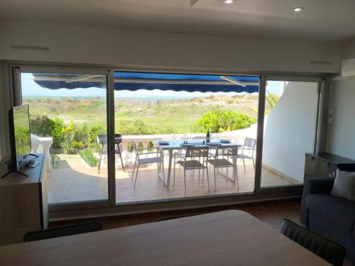 - un salon avec une table et des chaises sur une terrasse dans l'établissement Sol-y-Days Flamant, Superbe appartement en rez de jardin avec grande terrasse et jardinet, face a la mer, au Grau-du-Roi