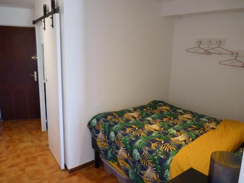 - une petite chambre avec un lit et une couverture colorée dans l'établissement Sol-y-Days Flamant, Superbe appartement en rez de jardin avec grande terrasse et jardinet, face a la mer, au Grau-du-Roi