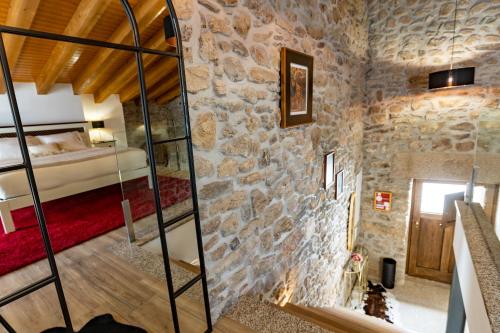 a room with a stone wall and a bedroom at Adega do Balé in Miranda do Douro