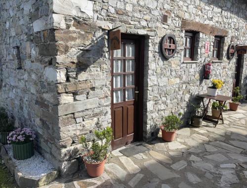 ein Steingebäude mit einer Holztür und Topfpflanzen in der Unterkunft Complejo la Regalina in Cadavedo