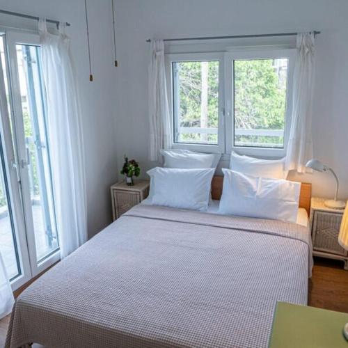 a bedroom with a large white bed with windows at Alemar Estates Agia Triada in Agia Triada