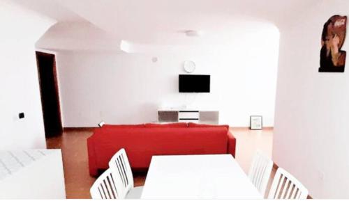 uma sala de estar com um sofá vermelho e uma mesa e cadeiras em Comfy Apartment with WiFi and Free Parking em Arguineguín