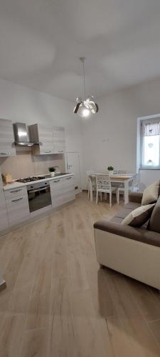 a white living room with a couch and a kitchen at Casa Francesca e Rooms in Santa Maria di Castellabate