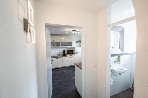 a white kitchen with white cabinets and a sink at City Wohnung FN L 5 KLIMATISIERT mit Balkon und Küche in Friedrichshafen