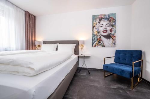 a hotel room with a large bed and a blue chair at City Wohnung FN L 5 KLIMATISIERT mit Balkon und Küche in Friedrichshafen