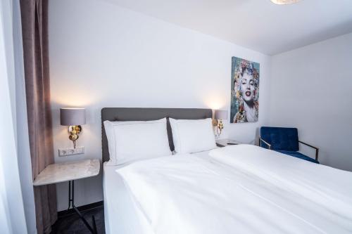 a bedroom with a white bed and a blue chair at City Wohnung FN L 5 KLIMATISIERT mit Balkon und Küche in Friedrichshafen