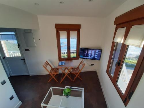 een woonkamer met een tafel en stoelen en een laptop bij Lighthouse Perlora vacaciones en el mar in Perlora