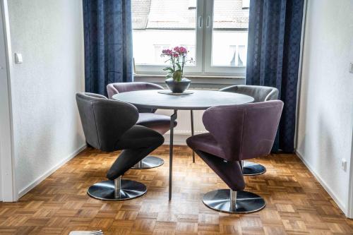 a table with four chairs and a vase of flowers on it at City Wohnung FN L 5 KLIMATISIERT mit Balkon und Küche in Friedrichshafen