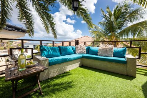 a blue couch on a balcony with a table at Apartment Lovely Rose with garden Jacuzzi in Jan Thiel