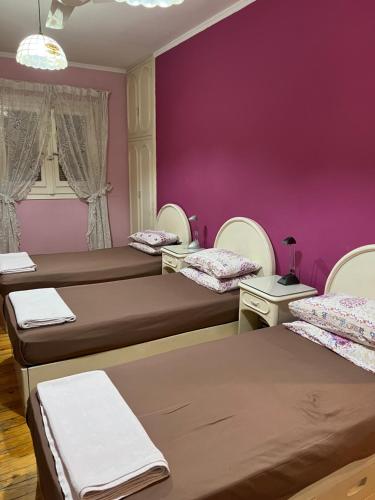 um quarto com três camas e uma parede roxa em very comfortable and cozy em Cairo