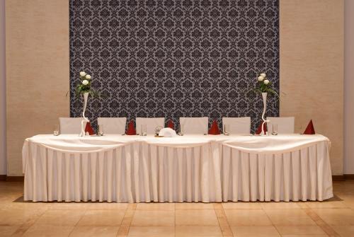 a group of tables with white table cloths and roses at Hotel Marand in Rzeszów