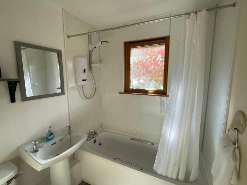 ein Bad mit einer Badewanne, einem Waschbecken und einer Dusche in der Unterkunft The Wee Hoose near Loch Ness, private garden, private parking in Drumnadrochit