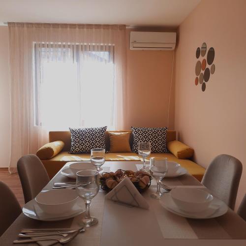 mesa de comedor con copas de vino y sofá en Апартамент Лидия en Chepelare