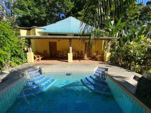 una piscina con sillas azules junto a una casa en Private Villa on 2-Acres of Jungle Garden & Pool, en Manzanillo