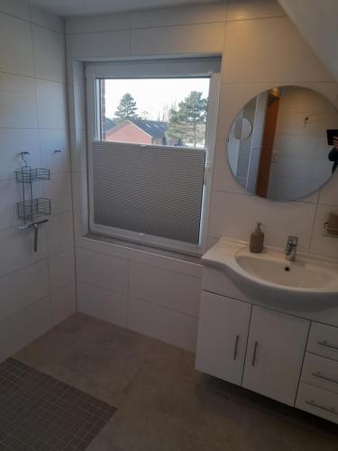 a bathroom with a sink and a mirror and a window at Fischerbalje in Borkum