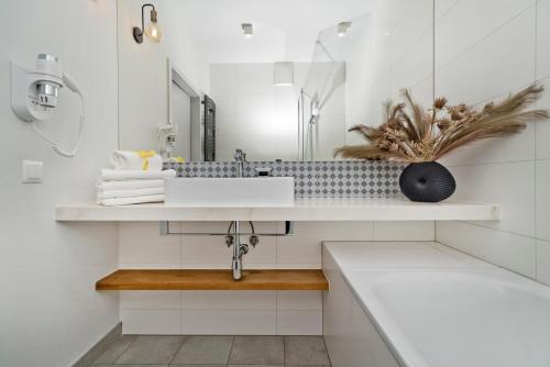 a white bathroom with a sink and a mirror at Aparthotel Anchoria BlueApart in Mechelinki