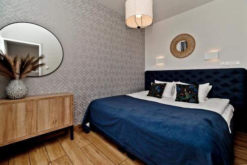 a bedroom with a blue bed and a mirror at Aparthotel Anchoria BlueApart in Mechelinki