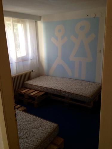 2 Betten in einem Zimmer mit geschlechtsspezifischen Schildern an der Wand in der Unterkunft BaselHostel in Füllinsdorf