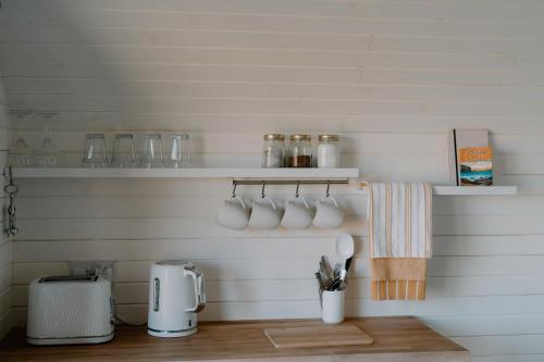 a kitchen with a counter with cups and utensils at Strathy Bay Pods in Strathy