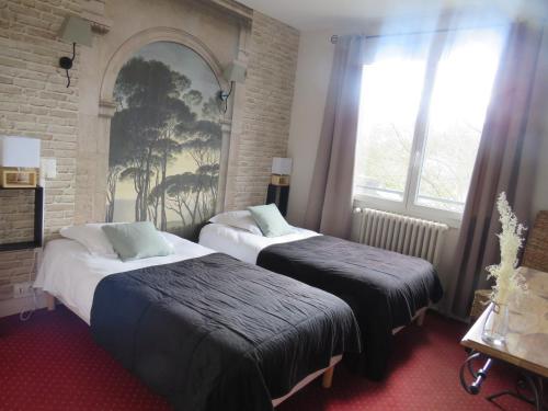 a hotel room with two beds and a window at Logis Hôtel Saint Cyr in La Ferté-Saint-Cyr