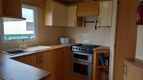 a small kitchen with a stove and a sink at A&P Sheron Holiday Home - The Chase, Ingoldmells, Skegness in Ingoldmells