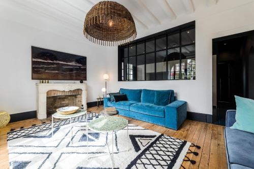 un salon avec un canapé bleu et une cheminée dans l'établissement VILLA FLOW KEYWEEK - heated pool garden Biarritz, à Biarritz