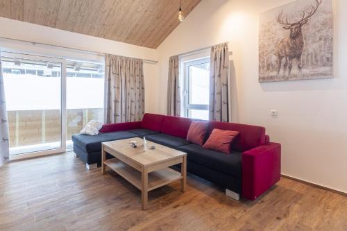 a living room with a red couch and a table at Bergresort Hauser Kaibling by ALPS RESORTS in Haus im Ennstal