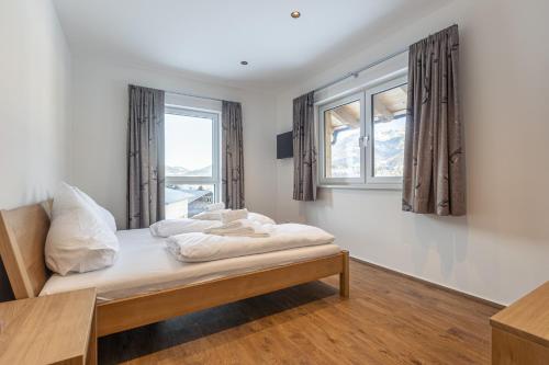a bedroom with a bed and two windows at Bergresort Hauser Kaibling by ALPS RESORTS in Haus im Ennstal