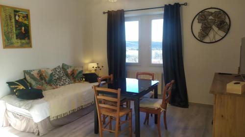 a living room with a table and a couch and a window at Le Gite du Gamin in Vagnas