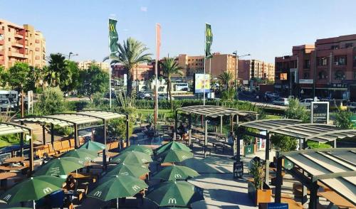 a group of tables with green umbrellas in a city at Royal Deluxe Silver - Marrakech, Luxe Pool View in Marrakech