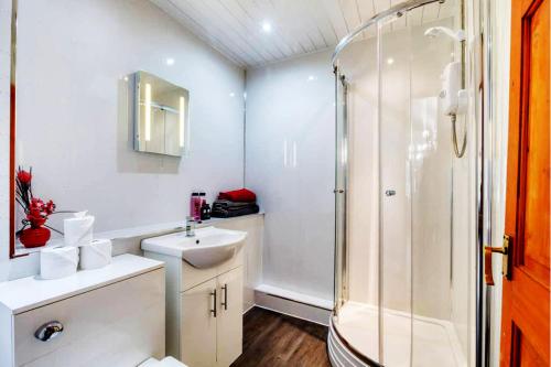 a white bathroom with a shower and a sink at Doocot At Bonnyside House in Bonnybridge