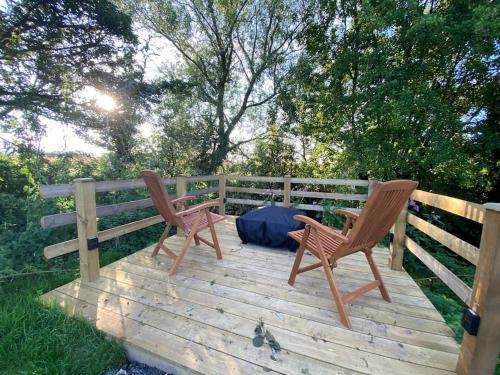 2 chaises assises au-dessus d'une terrasse en bois dans l'établissement Countryside Cabin, à Taunton