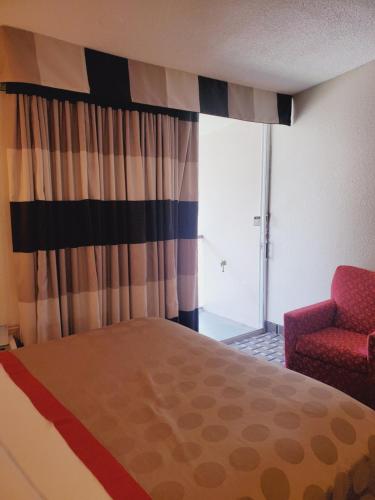 a bedroom with a bed and a chair and a window at Ramada by Wyndham Grand Junction in Grand Junction