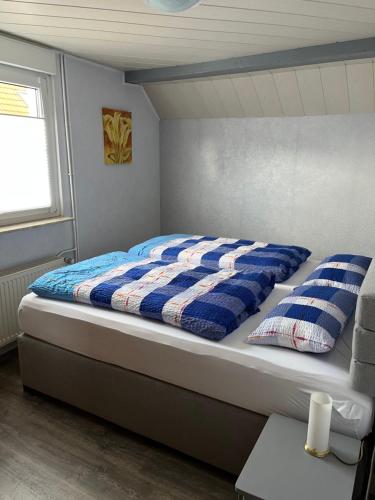 a bed with a blue and white comforter in a bedroom at Ferienhaus Sonnenschein Heyken in Werdum