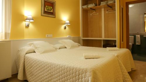 a bedroom with a large white bed with two pillows at Hotel Casa Benilde in Palas de Rei 