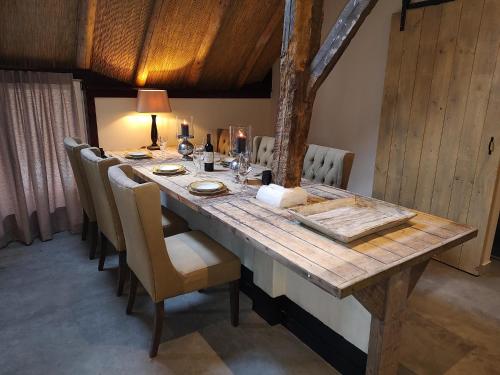 een lange houten tafel met stoelen en een tafel bij Juweeltje van vakantiewoning op prachtig landgoed in Nieuwleusen