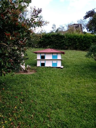 a small house with a red roof in the grass at Lago Calima - Bella Finca in Madroñal