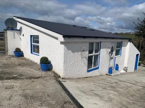 a small white house with blue windows and plants at The Honeycomb in Ballyshannon
