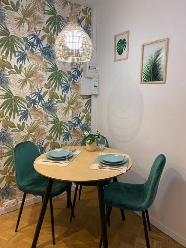 une salle à manger avec une table en bois et des chaises vertes dans l'établissement Vivez La forêt - Port de plaisance - Plage, au Havre
