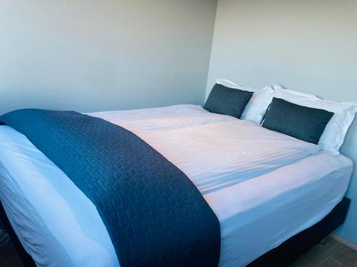a large bed with blue and white sheets and pillows at TB Penthhouse in Akureyri