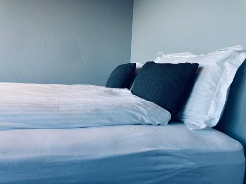 a bed with white sheets and a black pillow at TB Penthhouse in Akureyri