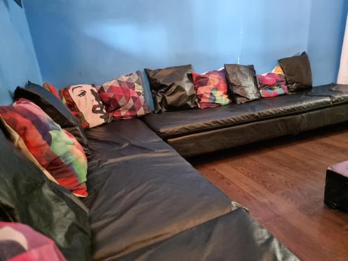 a black leather couch with many pillows on it at Windmill Hostel in Mendoza